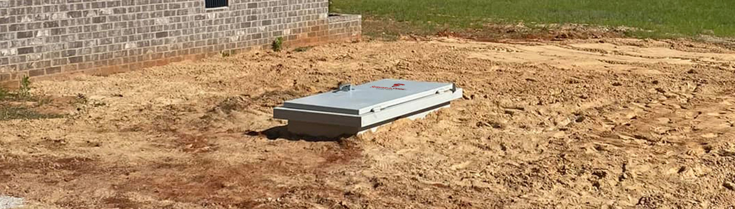 Underground storm shelter in a dirt lot